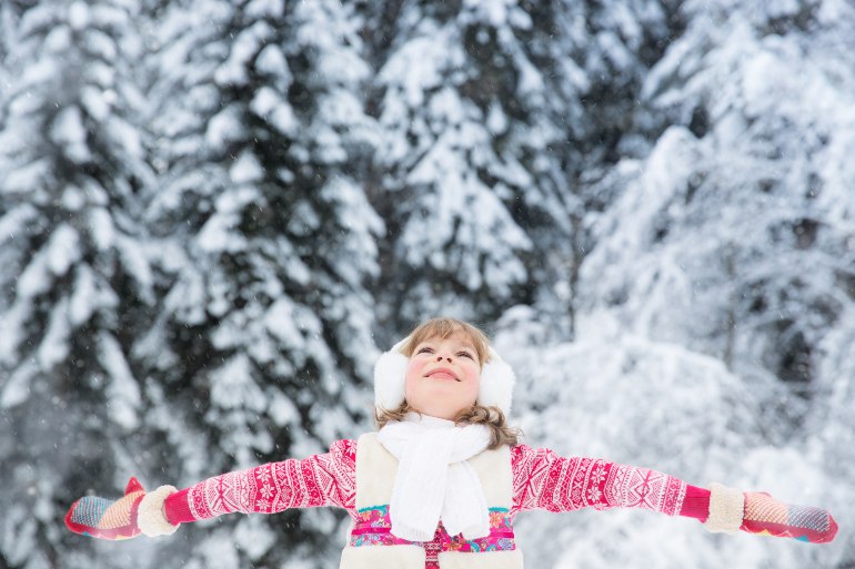 devojcica na snegu rasirenih ruku u crvenom dzemperu
