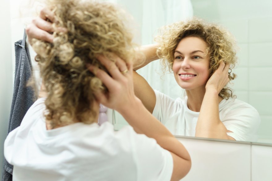 Žena stilizuje svoju kovrdžavu kosu